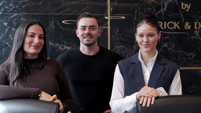 Aesthetify Berlin – Three team members in front of the dark marble wall with golden Aesthetify lettering
